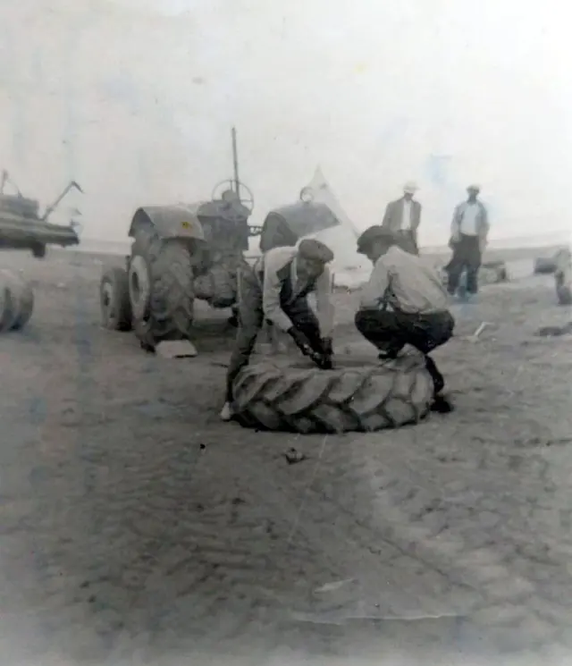 Eski siyah beyaz fotoğraf: tarlada traktör lastiği sökülüyor