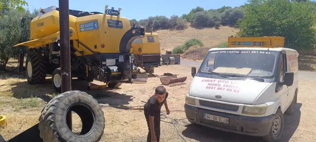 Tarlada sarı kombaynın lastiği mobil servis aracıyla yerinde değiştiriliyor